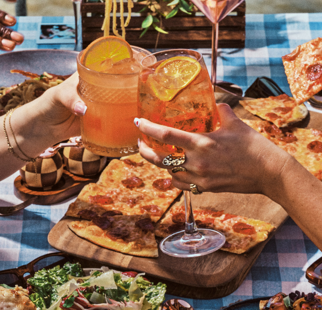 People clinking cocktail glasses in the sun 